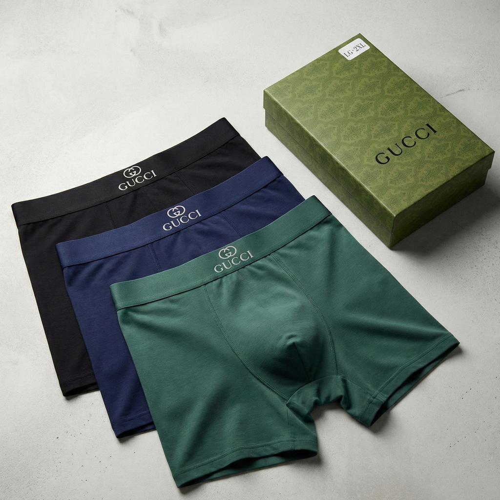 Three pairs of Gucci boxer briefs in black, blue, and green with a Gucci box on a light gray background.