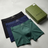 Three pairs of Gucci boxer briefs in black, blue, and green with a Gucci box on a light gray background.